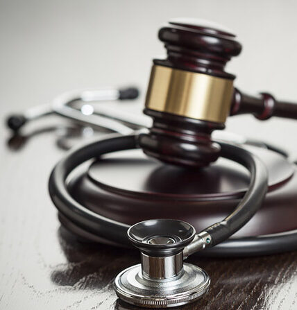 Gavel and Stethoscope on Reflective Wooden Table.